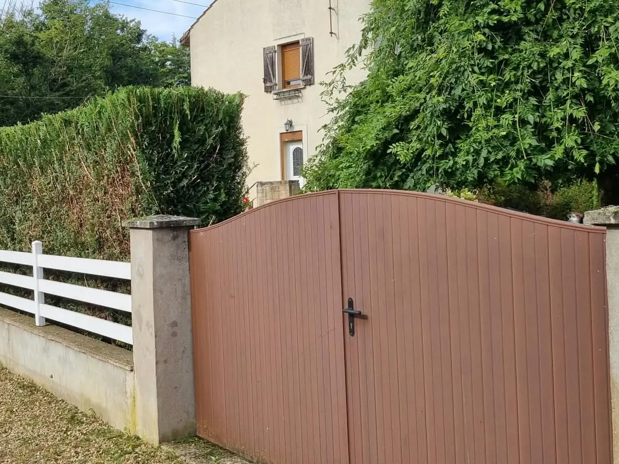 La même haie taillée droite, dessus et côtés, la clôture blanche dégagée et le talus tondu